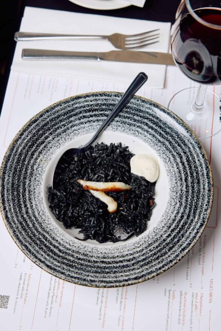 A dish of black ink rice topped with grilled octopus.