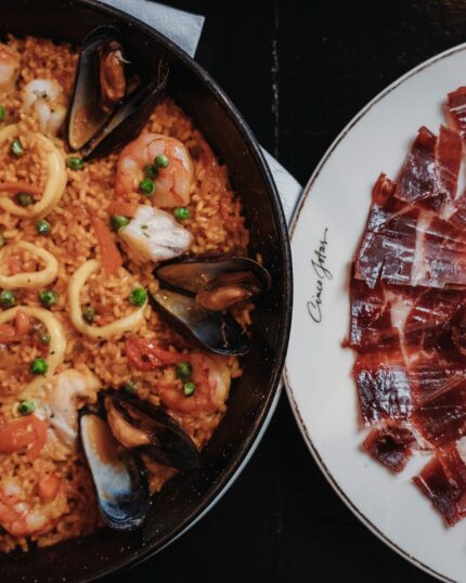 Freshly carved premium Iberian ham served alongside a traditional seafood paella.