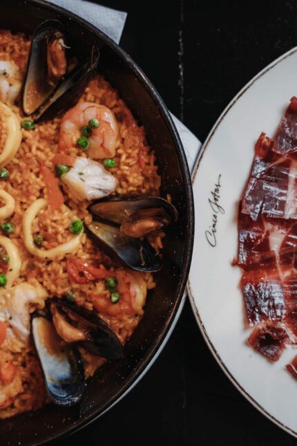 Jamón ibérico servido con paella de marisco en un restaurante.