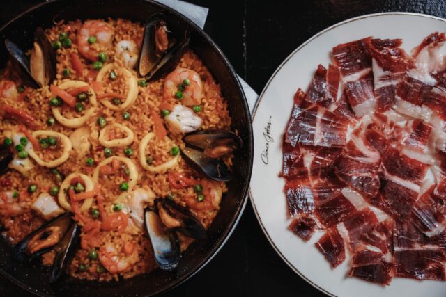 Jamon iberico served with seafood paella in restaurant