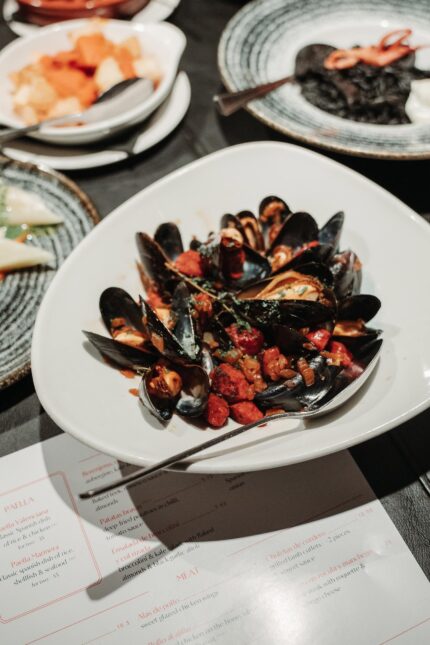A bowl of fresh mussels cooked in a rich chorizo and tomato sauce.