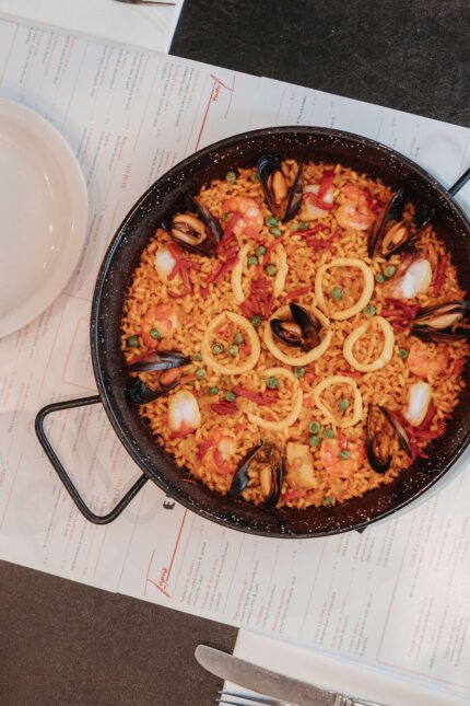 A traditional seafood paella served in a cast iron pan.