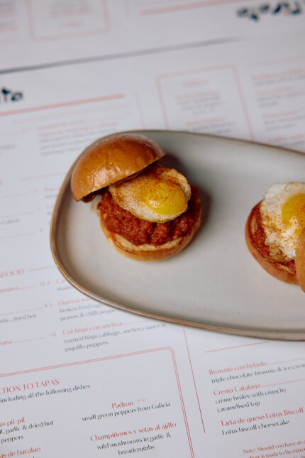 Three mini burger sliders served on a wooden board.
