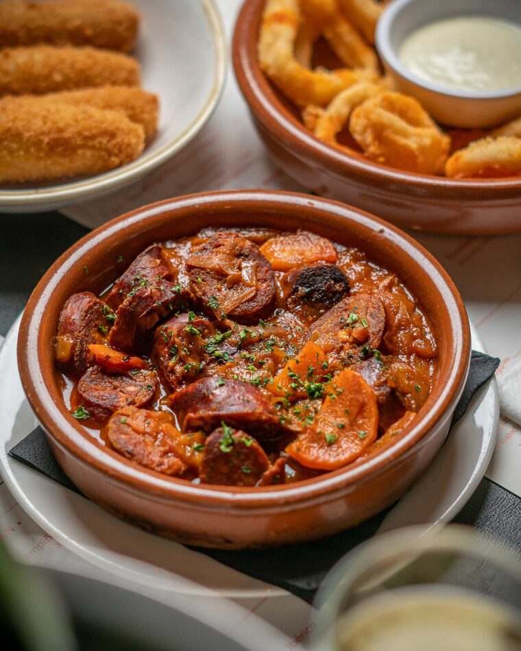Spanish tapas chorizo calamaris in traditional terracotta dishes