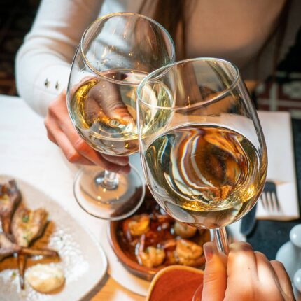 Two people toasting with glasses of red wine.